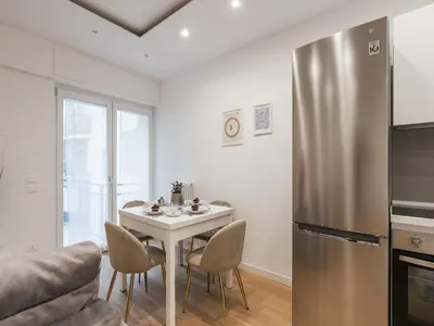 a kitchen with a white table and a stainless steel refrigerator at The Best Rent - Modern one-bedroom apartment in the Cipro area in Rome
