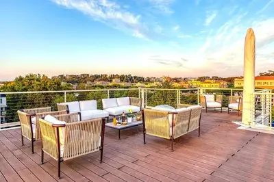 a deck with chairs and a couch and a surfboard at Skylife Tiber Luxury Penthouse in Rome