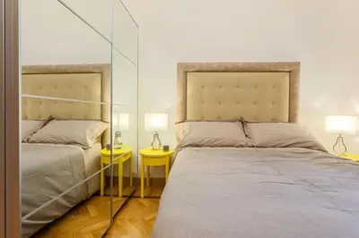 a bedroom with two beds and two lamps and mirrors at Vatican Loris House in Rome