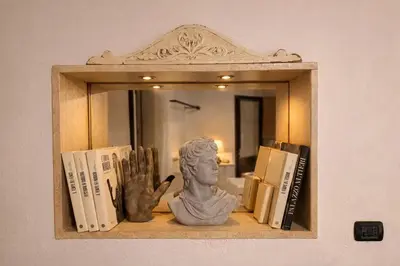 a shelf with books and a statue in front of a mirror at Piazza Navona Historic Escape in Rome