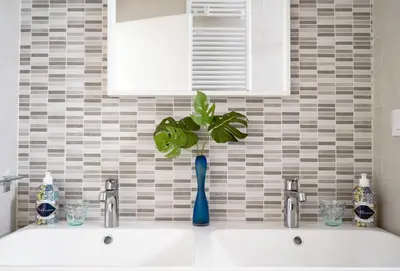 a bathroom sink with a blue vase with a plant in it at Vatican 23 Apartment in Rome