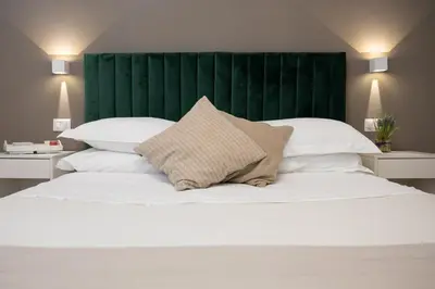 a white bed with a green headboard and white pillows at Maison Aurora in Rome