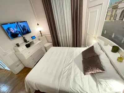 a white bedroom with a bed and a tv at Dimora Vantaggio in Rome