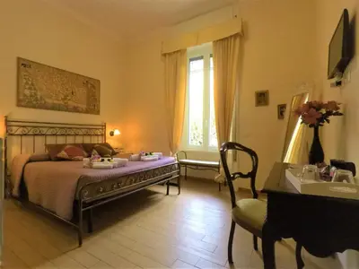 a bedroom with a bed and a chair and a window at Tucci's Roma Guest House in Rome