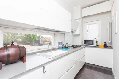 a kitchen with white cabinets and a large window at Elegant apartment metro A - by OpenRoma in Rome