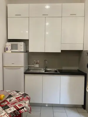 a white kitchen with a sink and white cabinets at La perla del Colosseo in Rome