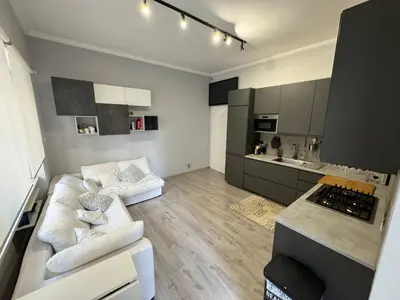 a living room with a white couch and a kitchen at Dolce Vita House - 10min walk to Vatican in Rome