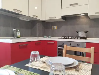 a kitchen with red cabinets and a table and a stove at La Casetta di Nonna Ro al Testaccio in Rome