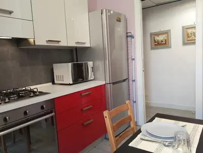a kitchen with red cabinets and a microwave and a table at La Casetta di Nonna Ro al Testaccio in Rome