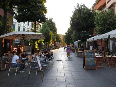 a group of people sitting at tables on a city street at Camere artistiche in appartamento in Rome