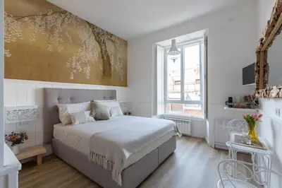 a white bedroom with a bed and a painting on the wall at Primo Piano Suites Garden in Rome