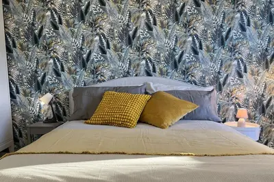 a bed with a yellow pillow in front of a wallpaper at Peter House in Rome