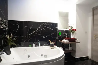 a bathroom with a white tub and a black wall at farnese jacuzzi apartment in Rome