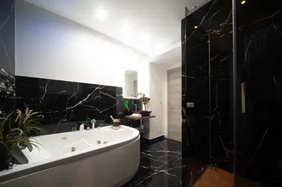a bathroom with a white tub and a black wall at farnese jacuzzi apartment in Rome
