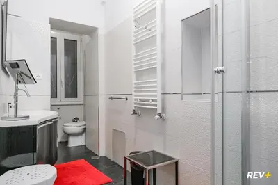 a white bathroom with a toilet and a red rug at Art Apartment Rome City Center in Rome