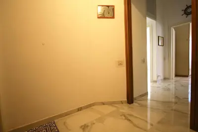 a hallway with a white wall and a tile floor at Graziano Holiday House in Rome