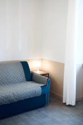 a blue couch sitting in a room with a lamp at Cozy Apartment in the heart of Garbatella in Rome
