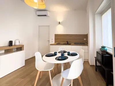 a white kitchen with a white table and white chairs at Gozzadini Apartment in Rome