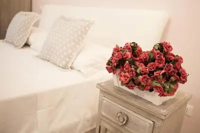 a bouquet of red roses on a table next to a bed at B&B Vatican's Keys in Rome