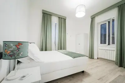 a white bedroom with a bed and a window at Maison Salvia in Rome