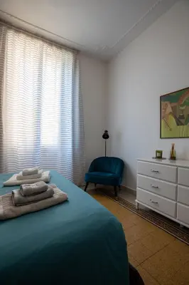a bedroom with a blue bed and a blue chair at UrbanPiramide - Roma in Rome