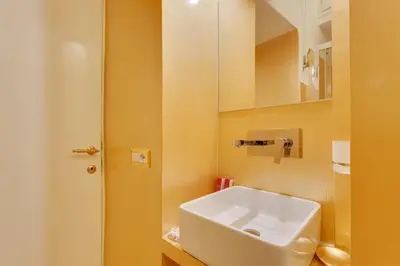 a bathroom with a white sink and a mirror at Spanish Steps Boutique Gold Apartment in Rome
