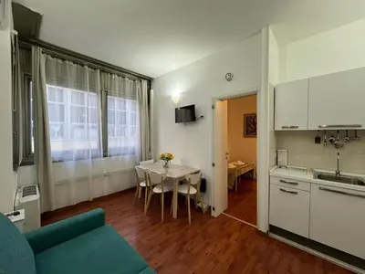 a kitchen and a living room with a table and a couch at San Giovanni's Cozy Apartment in Rome