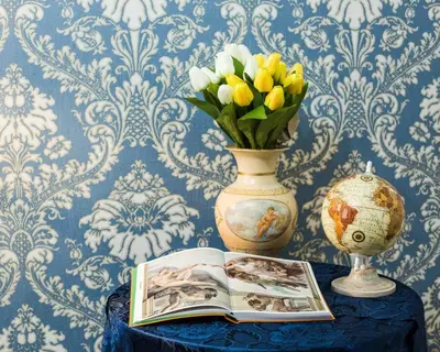 a table with a vase and a book and flowers at Apartment Glatimia -Your Home In The Heart Of Rome in Rome