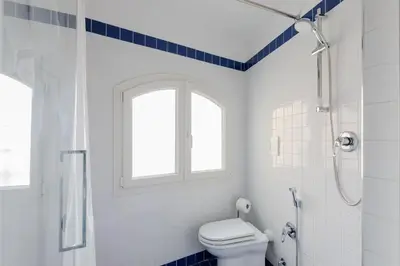 a white bathroom with a toilet and a window at Residenza del Cedro in Rome
