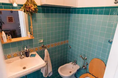 a green tiled bathroom with a toilet and a sink at Lovely Sanctuary Central in Rome