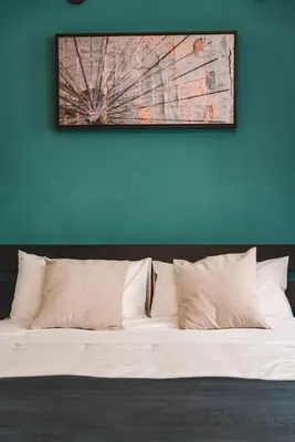 a bed with white pillows against a blue wall at Cosy Colosseum in Rome
