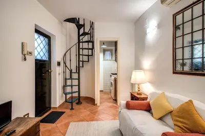 a living room with a couch and a spiral staircase at Charlotte Luxury Home Coronari in Rome