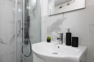 a white bathroom with a sink and a shower at San Paolo Suites Metro Station in Rome