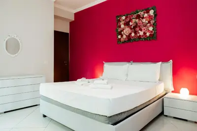 a bedroom with a white bed with a red wall at Romantic Malatesta in Rome