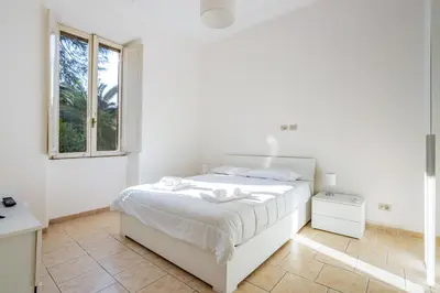 a white bedroom with a white bed and a window at LA DOLCE VITA - stone's throw from the city center in Rome
