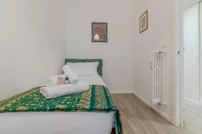 a white bedroom with a bed with a green and white blanket at Journalist Apartment Sistine Chapel in Rome