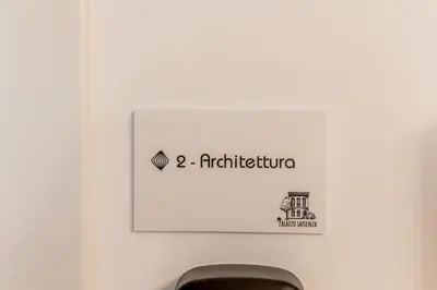 a sign on a wall above a toilet in a bathroom at Palazzo Sapienza Design Suites in Rome