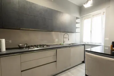 a kitchen with white cabinets and black counter tops at Jmartins Vatican Apartment in Rome