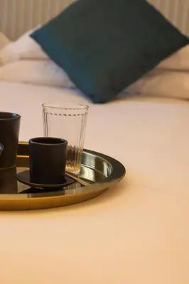 a tray with two cups and a glass on a bed at Tiburtina 86 Luxury Suites in Rome