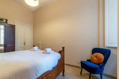 a bedroom with a bed and a blue chair at GuestHost - Sapienza University Elegant Apartment! in Rome
