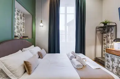 a bedroom with a bed with white sheets and pillows at Vivilo Collection - Charme 24 Suites - Close to Via Veneto in Rome