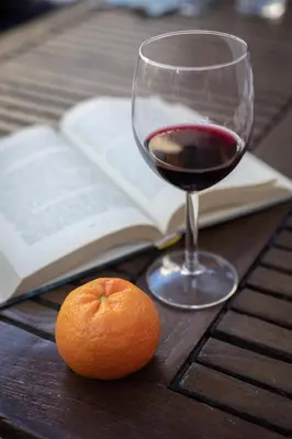 an orange and a glass of wine on a wooden table at NOBILIA - Roof Garden Penthouse near Navona Square in Rome