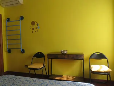 two chairs and a table in a room with a yellow wall at Maddy House Roma in Rome