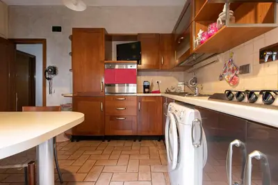 a kitchen with wooden cabinets and a white dishwasher at Maddy House Roma in Rome