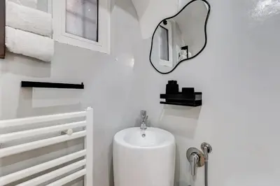 a white bathroom with a sink and a mirror at Vicolo Sereno Roma in Rome