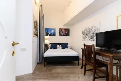 a room with a bed and a desk and a television at Colosseum Apartment with Terrace by NDP rent in Rome