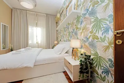 a bedroom with a bed with a tropical wallpaper at Lucky Domus Tuscolano in Rome