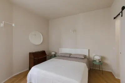 a bedroom with a white bed and a clock on the wall at Modern Spacious Apartment on the Tevere in Rome
