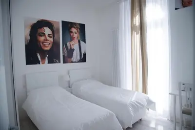 two beds in a white bedroom with posters on the wall at Big Johnny B in Rome