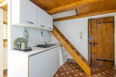 a kitchen with white cabinets and a wooden door at little house in trastevere in Rome